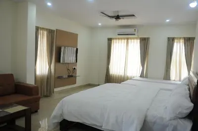 a bedroom with a large white bed and a couch at Amma Inn Elegance Suites and Apartments in Mysore