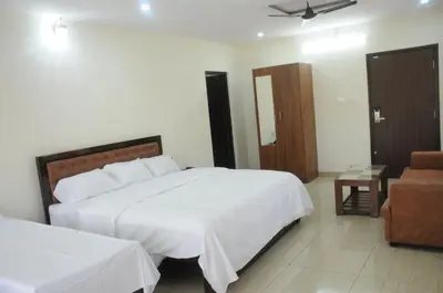 a bedroom with a large white bed and a chair at Amma Inn Elegance Suites and Apartments in Mysore