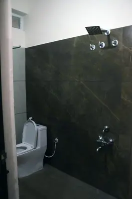 a bathroom with a toilet and a light on the wall at Amma Inn Elegance Suites and Apartments in Mysore