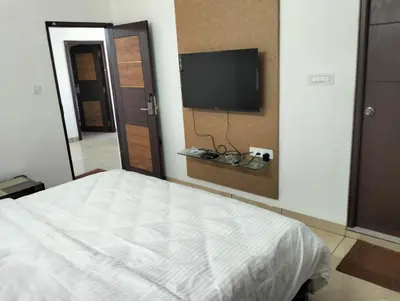 a bedroom with a bed and a flat screen tv at Amma Inn Elegance Suites and Apartments in Mysore