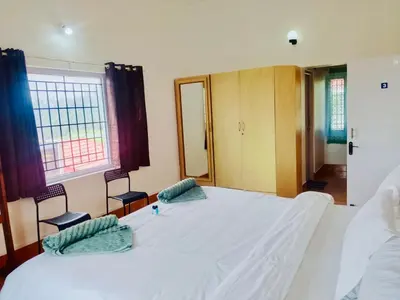 a bedroom with a large white bed with two chairs at Teyt's White Home - 3 bedroom Villa in Ooty