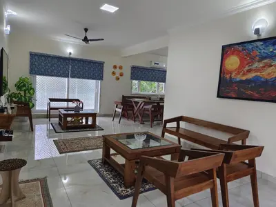 a living room with wooden furniture and a painting on the wall at 7 Elysee Homestay - Onyx - Premium 3BHK Family Flat in Trichūr