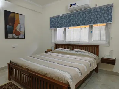 a bedroom with a bed and a window with a air conditioner at 7 Elysee Homestay - Onyx - Premium 3BHK Family Flat in Trichūr