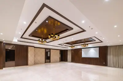a large ballroom with a projection screen and chandeliers at Royal Embassy in Erode