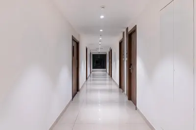 an empty corridor of a building with white walls and white floors at Royal Embassy in Erode