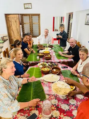 a group of people sitting around a table eating food at Green Island Homestay Riverside in Kozhikode