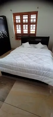 a large white bed in a bedroom with two windows at Green Island Homestay Riverside in Kozhikode