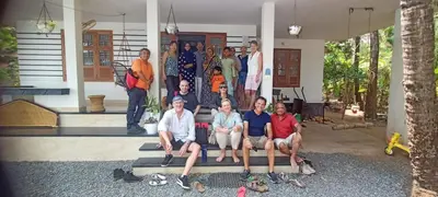 a group of people sitting on the steps of a house at Green Island Homestay Riverside in Kozhikode