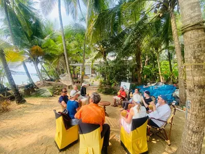 a group of people sitting in chairs on the beach at Green Island Homestay Riverside in Kozhikode