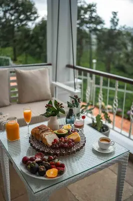 a table with a plate of food on a balcony at LohonoStays Villa Lansdowne in Coonoor