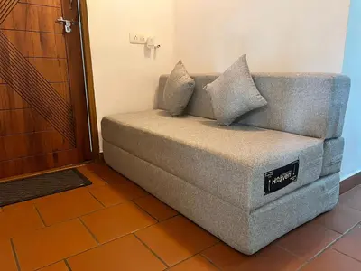 a couch sitting in the corner of a room at Gangadharam Tiny House 2BHK AC in Tellicherry