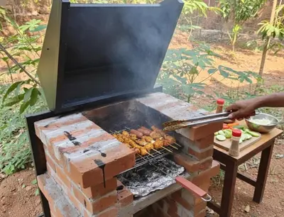 a person is cooking food on a grill at Gangadharam Tiny House 2BHK AC in Tellicherry