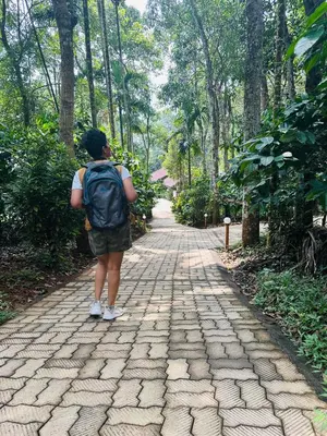 a person with a backpack walking down a brick road at Drey at Druv Dakshin Farm Resort in Padinjarathara
