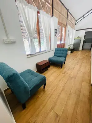 a living room with two blue couches and a wooden floor at Drey at Druv Dakshin Farm Resort in Padinjarathara