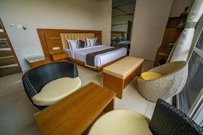 a bedroom with a bed and chairs and a table at S R Pool Suites in Mysore
