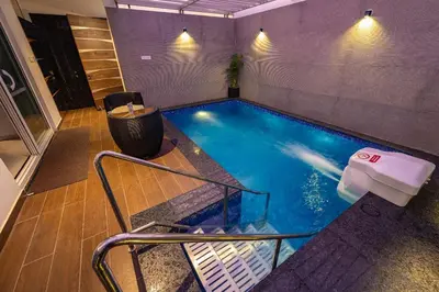 a small swimming pool in a room with a table at S R Pool Suites in Mysore