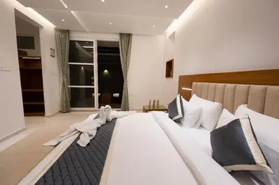 a bedroom with a large bed with white sheets at S R Luxury Stays in Mysore