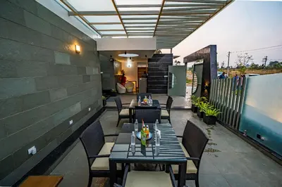 a patio with tables and chairs on a balcony at S R Luxury Stays in Mysore
