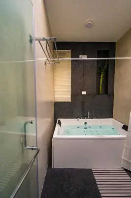 a bathroom with a tub and a glass shower at S R Spa Suites in Mysore