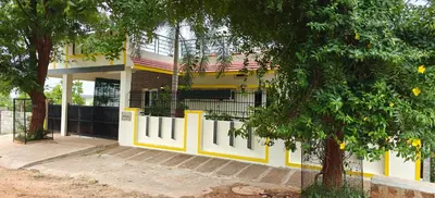 a yellow and white building with a gate and trees at S R Villa Mysore in Mysore