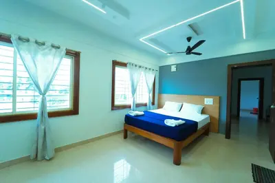 a blue bedroom with a bed and two windows at GLN Residency Pure Veg in Kālvādi