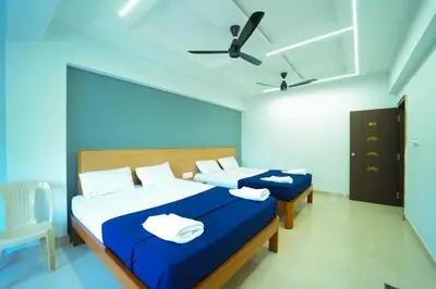 a bedroom with two beds and a ceiling fan at GLN Residency Pure Veg in Kālvādi