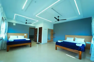 two beds in a room with blue walls at GLN Residency Pure Veg in Kālvādi