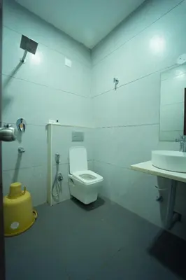 a white bathroom with a toilet and a sink at GLN Residency Pure Veg in Kālvādi