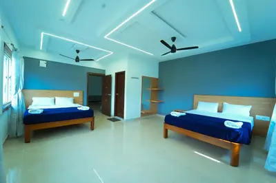 two beds in a room with blue walls at GLN Residency Pure Veg in Kālvādi