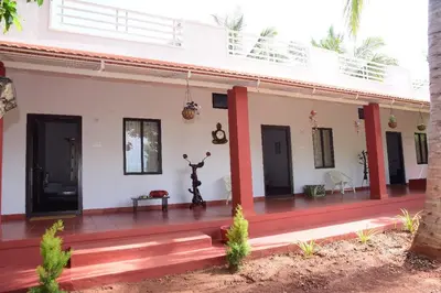 a white house with a porch and a deck at Aastha homestay in Mysore