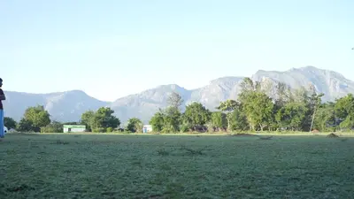 a person standing in a field with mountains in the background at Wild Tusker Homestay Masinagudi by LexStays in Masinagudi