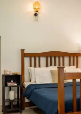 a bed with a wooden headboard and a night stand at The Anexure - Great Estate Stay for Remote Work in Siddapur