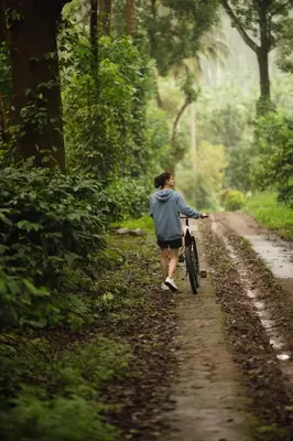 a woman walking a bike down a dirt road at The Anexure - Great Estate Stay for Remote Work in Siddapur