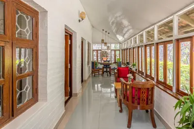 a hallway with windows and a table and chairs at The Anexure - Great Estate Stay for Remote Work in Siddapur