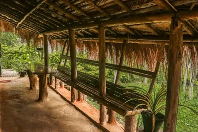 a bench sitting under a hut in the grass at The Soul Marayoor Mudhouse - Munnar in Marayoor