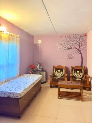 a bedroom with a bed and two chairs and a tree mural at Preetham Homestay in Kushālnagar