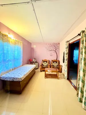 a bedroom with a bed and two chairs in it at Preetham Homestay in Kushālnagar