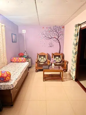 a room with two beds and a tree mural on the wall at Preetham Homestay in Kushālnagar