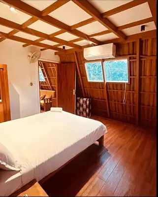 a bedroom with a white bed and wooden floors at Hill View 'A'Frame Villa Wayanad in Vythiri
