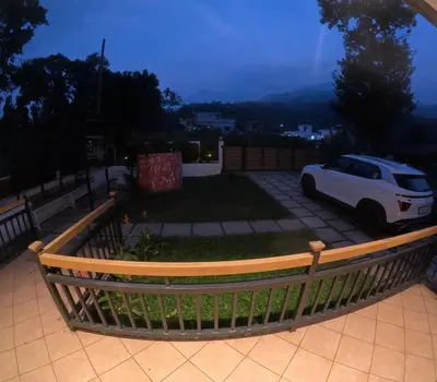 a white car parked in a yard with a fence at Hill View 'A'Frame Villa Wayanad in Vythiri