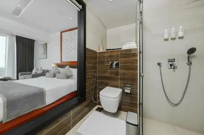 a bathroom with a shower and a bed and a toilet at TIARA by MPS in Kozhikode