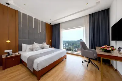 a hotel room with a bed and a desk and a window at TIARA by MPS in Kozhikode