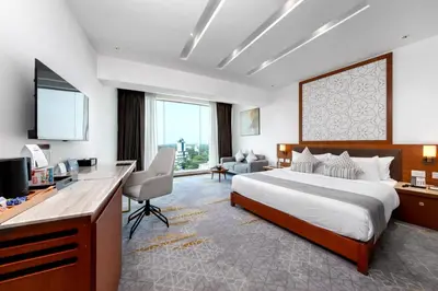 a hotel room with a bed and a desk and a television at TIARA by MPS in Kozhikode