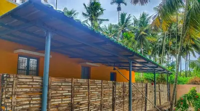 a building with a blue roof with palm trees at Coconut Grove villa by Shivalaya Stays in Alāndurai