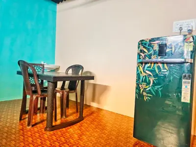 a table and two chairs next to a refrigerator at Coconut Grove villa by Shivalaya Stays in Alāndurai