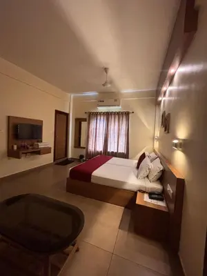 a hotel room with a bed and a chair at Maharani Hotel in Kozhikode