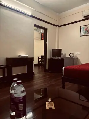 a living room with a couch and a tv at Maharani Hotel in Kozhikode