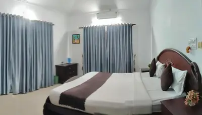 a bedroom with a large bed with blue curtains at Illam Heritage inn Bungalow l 4 BHK in Guruvāyūr