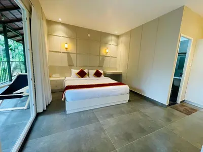 a bedroom with a bed and a balcony at The Hive at Druv Dakshin Farm Resort in Padinjarathara
