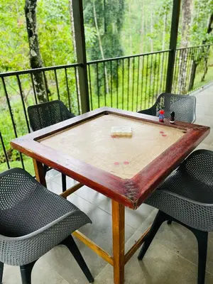 a wooden ping pong table on a porch with two chairs at The Hive at Druv Dakshin Farm Resort in Padinjarathara